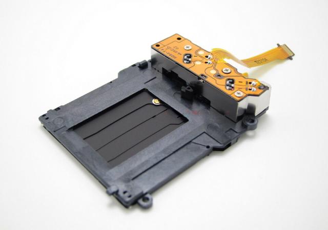 Photo of a digital camera shutter mechanism spare part.